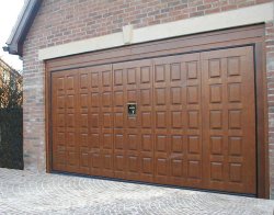 Remote control timber garage door by Silvelox with pedestrian door available in oak, larch or mahogany